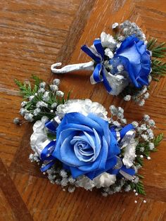 two blue and white flowers are sitting on a wooden table next to other bouquets