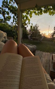 a person is reading a book while sitting in a hammock on the deck