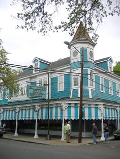 two people are standing on the sidewalk in front of a blue and white building with a clock tower