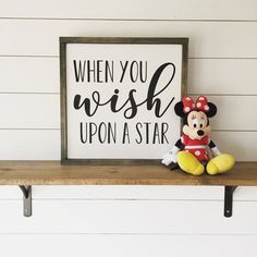 a mickey mouse sitting on top of a shelf next to a sign that says when you wish upon a star