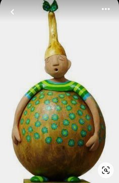 a ceramic sculpture of a person sitting on top of a large ball with a green hat