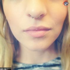 a close up of a woman with a nose piercing on her nose and long blonde hair