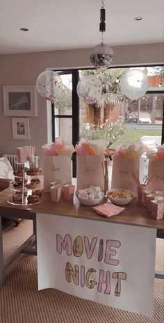 a table that has some cupcakes on it with movie night signs in front of it