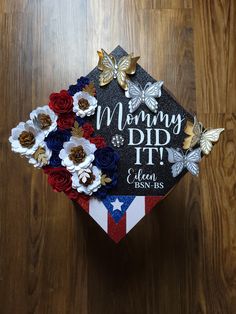 a graduation cap decorated with flowers on top of a wooden floor and the words, mommy did it?