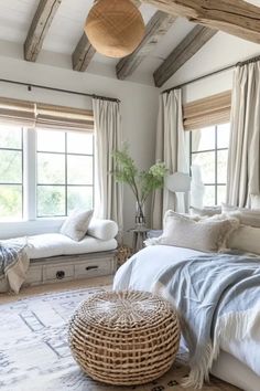 a bed room with a neatly made bed and two pillows on the floor next to windows