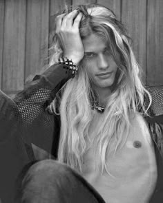 black and white photograph of a shirtless man with long hair sitting on the ground