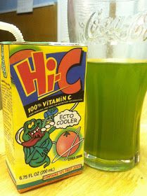 a green drink sitting on top of a wooden table next to a carton of vitamin c