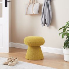 a yellow foot stool sitting in front of a white door next to a potted plant