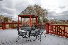 a table and chairs on a deck with a gazebo in the background