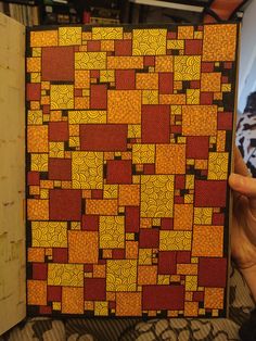 a person holding up a piece of art made out of squares and rectangles