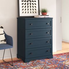 a blue chest of drawers sitting on top of a wooden floor next to a chair