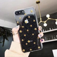 a woman holding up an iphone case with stars on it