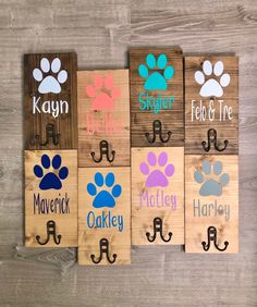 four wooden signs with different colored paw prints and the names of each dog's paws