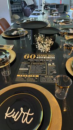 the table is set with black plates and gold rimmed place settings for dinner guests