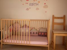 a child's room with a crib, chair and wall decal that says edith