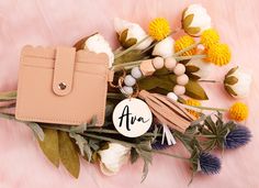 a pink purse with a name tag on it and some flowers around the bag that says am