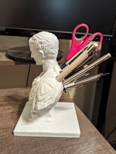 a white statue with scissors in it on top of a table