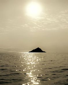 the sun shines brightly on an island in the middle of the ocean as it reflects off the water