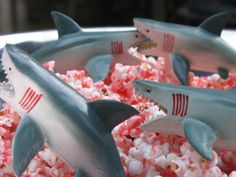 three shark figurines sitting on top of popcorn in the shape of fish and sharks