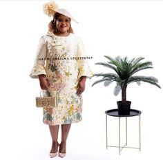 a woman in a dress and hat standing next to a potted plant on a table