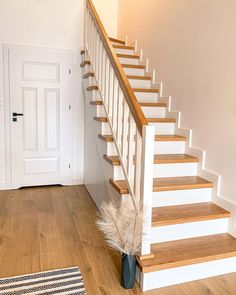 there is a vase with some flowers on the floor next to the stairs in this house