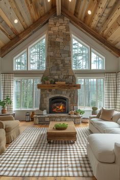 a living room with a large stone fireplace and lots of windows on the side of it