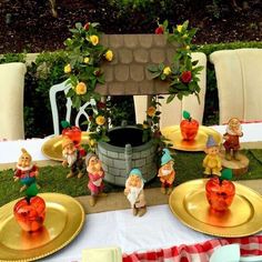 the table is set with gold plates and gnome figurines