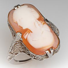 This antique filigree cameo ring features an elongated shell cameo of a woman's bust. The ring was loved and worn over the years and the cameo bust is a bit worn. The ring itself has crisp and strong details with open scroll work and milgrain. The ring is crafted in 10k white gold and is currently a size 5. The cameo is glued in for security. Luxury Cameo Wedding Rings, Antique Cocktail Ring, Antique Filigree, Scroll Work, Cameo Ring, Vintage Cameo, Ring White Gold, Conceptual Art, White Ring