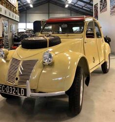 an old yellow car parked in a garage