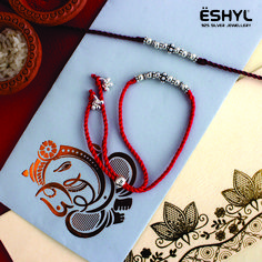 a red string bracelet with an elephant design on it next to a greeting card and some other items