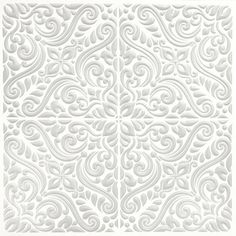 an intricate white paper cutout with swirls and leaves on the sides, in three different