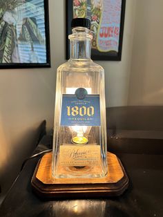 a bottle of booze sitting on top of a wooden tray in front of pictures