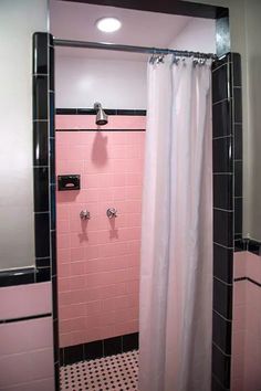 a pink bathroom with black and white flooring, shower curtain, and tiled walls