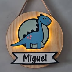 a wooden sign that says miguel with a cartoon dinosaur on it's back side