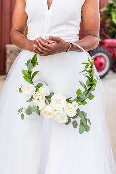 a woman in a white dress holding a flower wreath