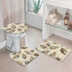 three bathroom rugs with shells on them in front of a sink and toilet next to a window