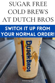 a cup of ice cream sitting on top of a wooden table with the words, sugar free cold brews at dutch bros switch it up from your normal order