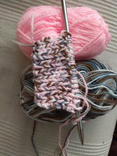 two balls of yarn sitting next to each other on top of a white cup with a crochet hook