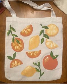 a white bag with oranges and lemons painted on the side, sitting on a wooden floor