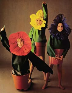 three children dressed up in costumes and holding umbrellas, posing for the camera with their hands raised