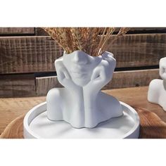 a white elephant statue sitting on top of a wooden table next to a vase filled with dry grass