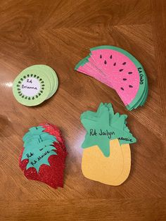 three pieces of paper cut out to look like fruit sitting on a wooden table top