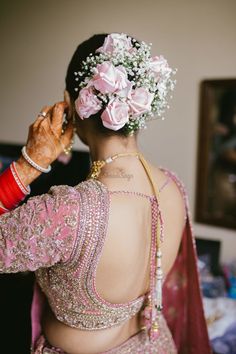 the back of a woman's head with flowers in her hair and jewelry on