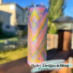 a pink and yellow vase sitting on top of a wooden table next to a fence