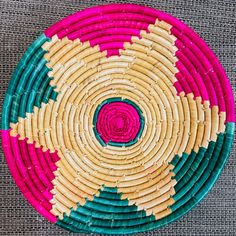 a colorful woven basket with pink, green and yellow designs on it's sides