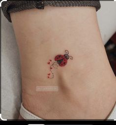 a ladybug tattoo on the side of a woman's stomach is shown