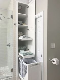 an open door to a walk in shower next to a white cabinet with towels on it