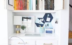 a white desk topped with lots of books next to a book shelf filled with books