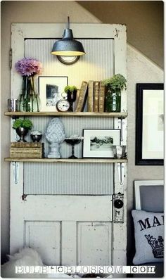 an old door is open to reveal a shelf with flowers and pictures on it in the corner