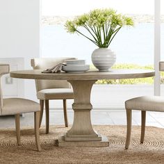 a dining room table with two chairs and a vase on top of it, in front of a window